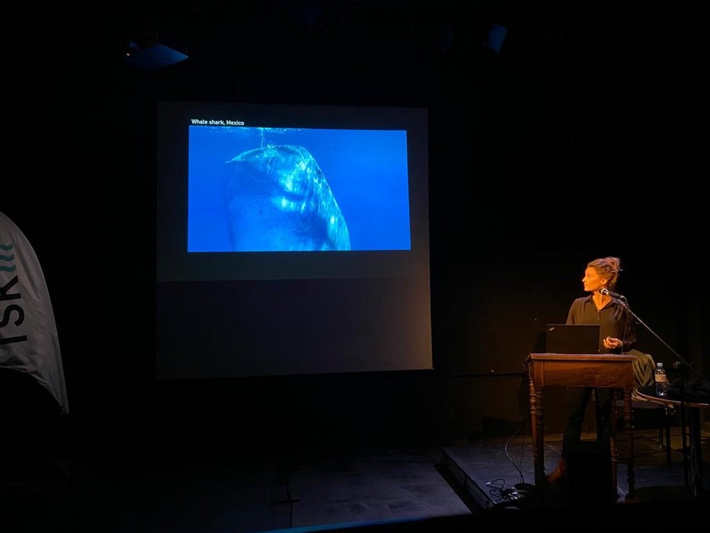 Junge Frau neben Screen am Vortrag über Haie