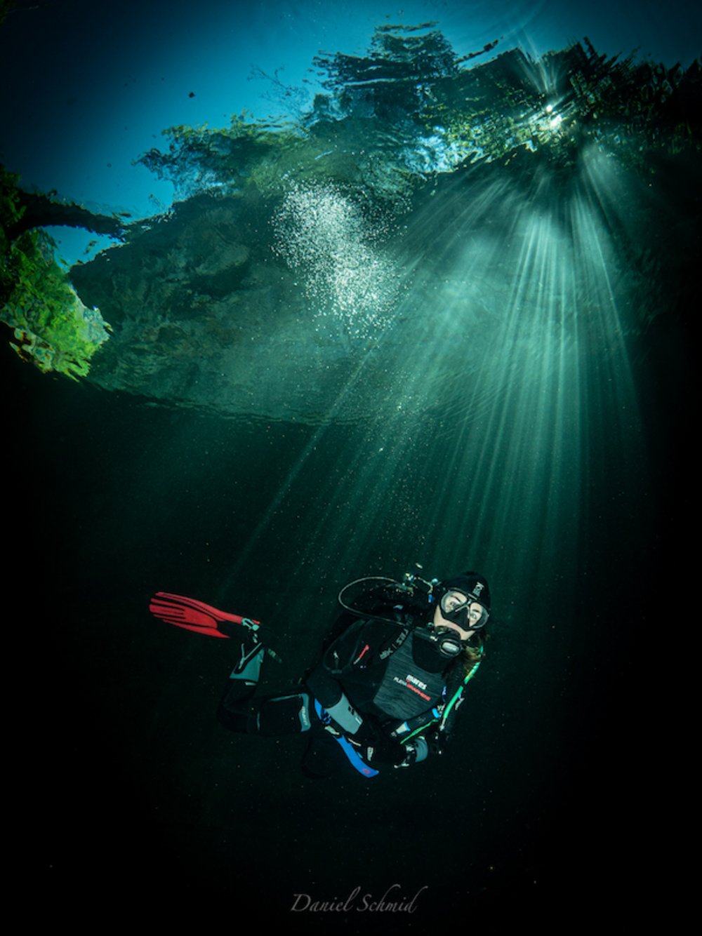 Unterwasser Fotografie von einer Taucherin im Fluss. Die Sonne schein durch die Wasseroberfläche und zeichnet wunderschöne Strahlen ab. 